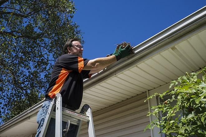 a worker using tools to fix a broken gutter in Asbury